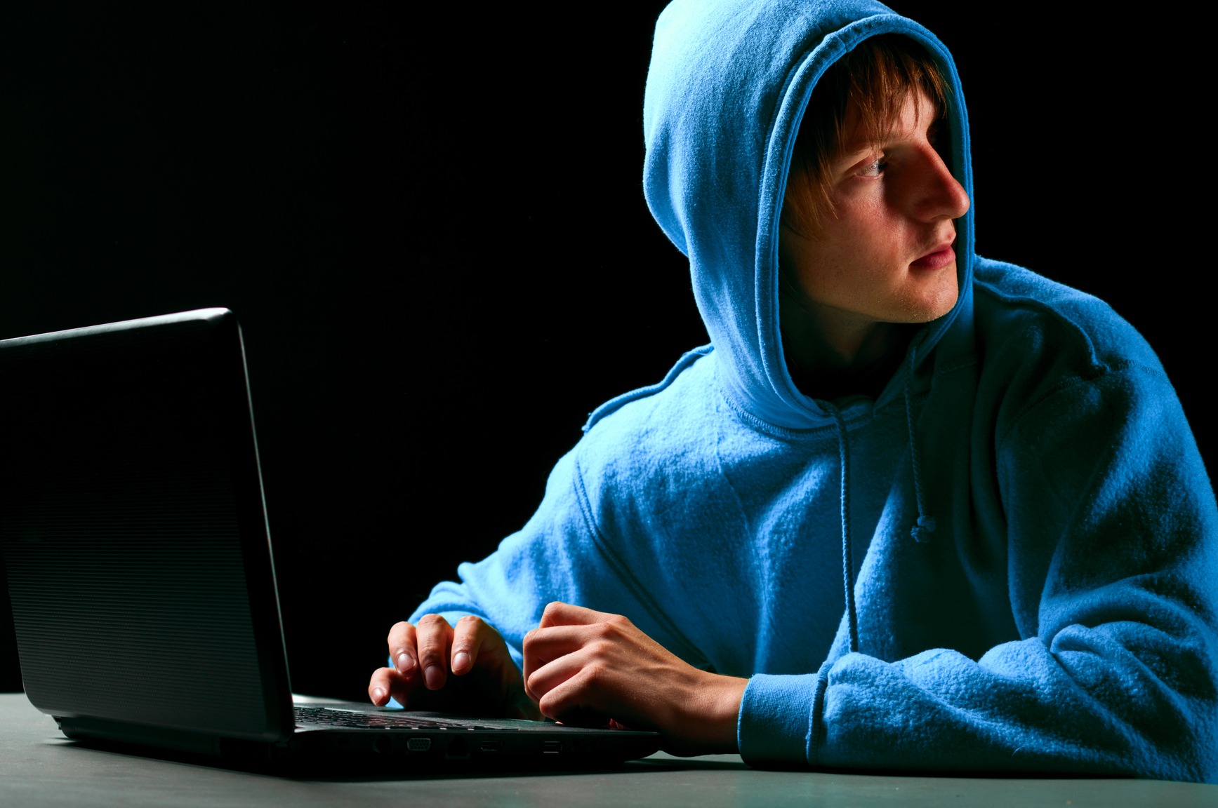 hacker. Young man with laptop is looking back